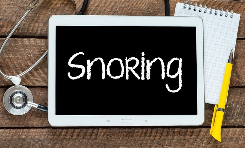 Word snoring written on tablet with stethoscope and pen and paper on wood background.