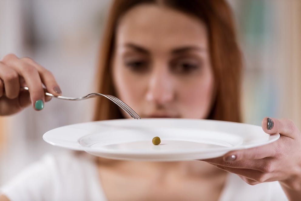 a picture of a woman with one tiny piece of food on her plate