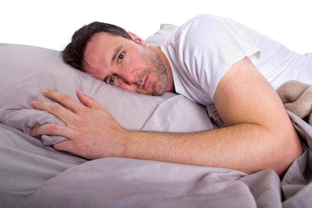 A close-up of a man lying in bed who can’t sleep because of fasting