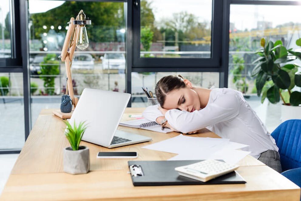 An exhausted businesswoman sleeping at her desk in front of her computer