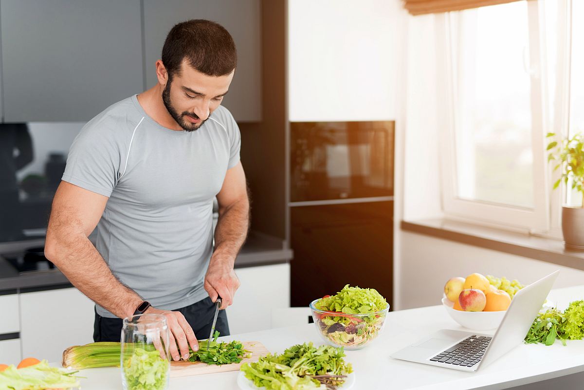 A sporty man is preparing a salad in the kitchen | A Beginner's Overview to Keto and Intermittent Fasting | intermittent fasting and keto