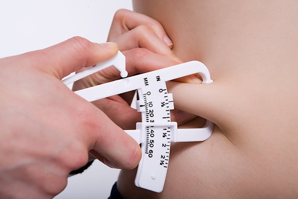 a photo of a person measuring someone’s body fat with calipers