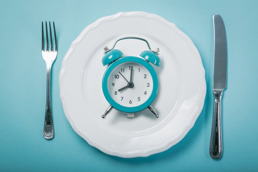 Clock, plate, and silverware on blue table | Rid Your Back Fat The Fastest Way