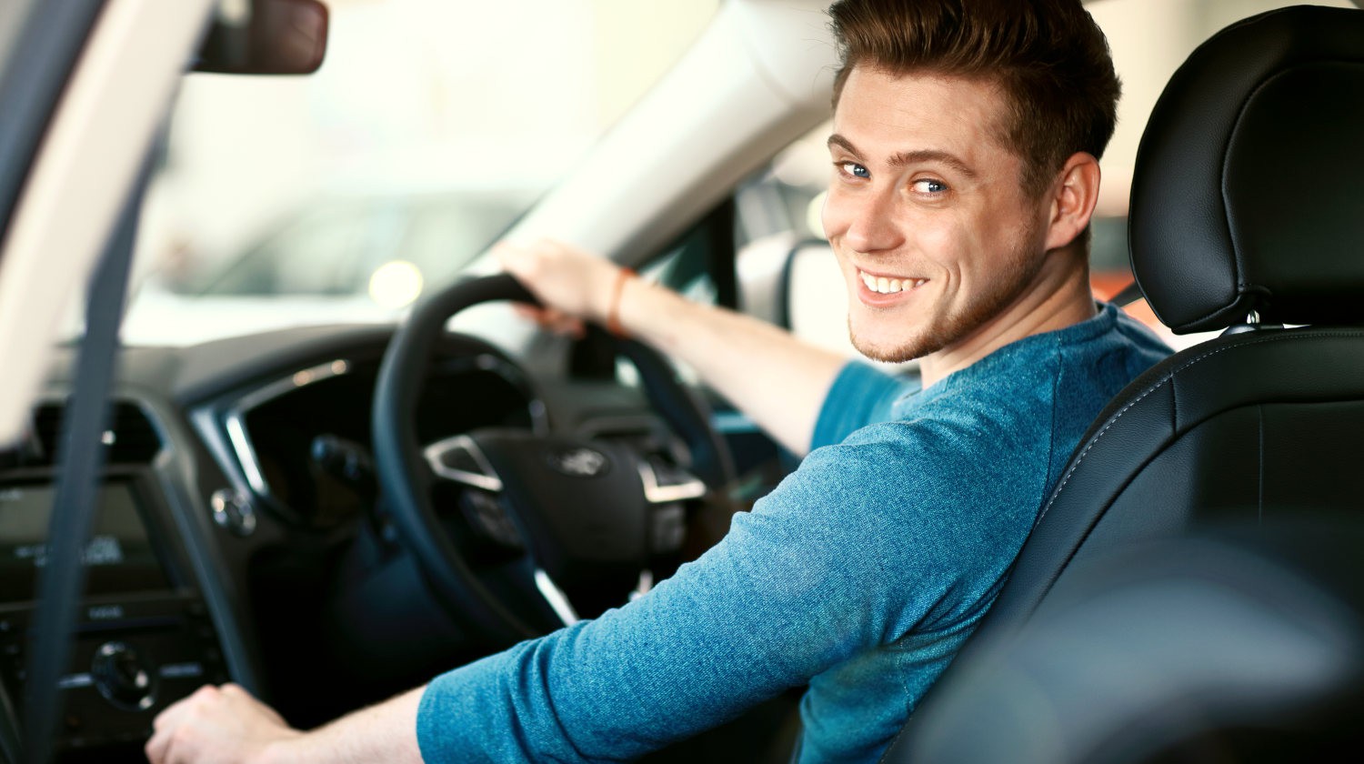 Featured | Happy young male driver behind the wheel | Road Trip Food: Eating While Traveling on Keto Diet