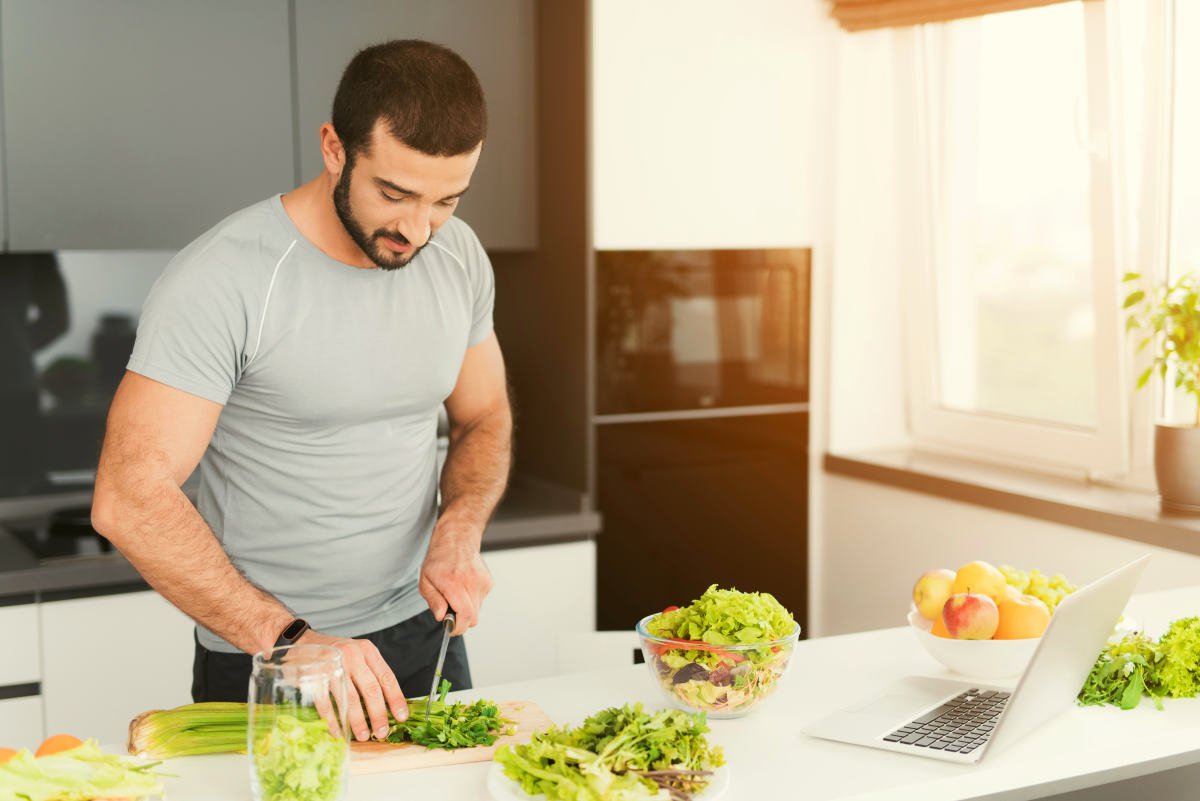 A sporty man is preparing a salad in the kitchen | Road Trip Food: Eating While Traveling on Keto Diet