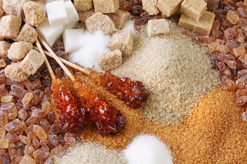 Various kinds of sugar including brown sugar, white cane sugar, sugar cubes, crystals, coconut sugar.