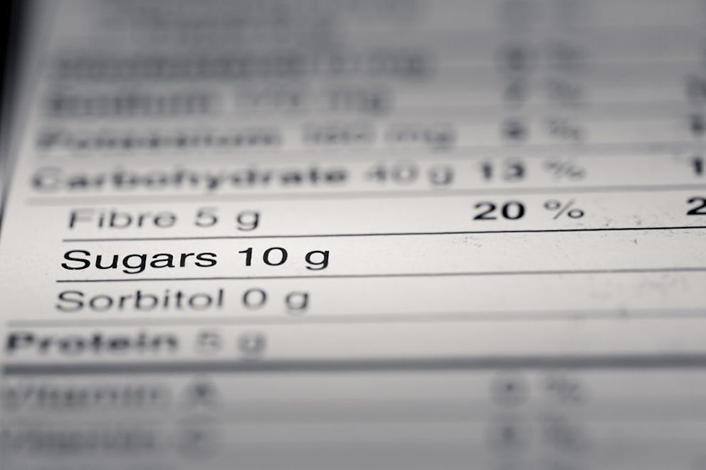 Nutrition facts food label information focused on grams of sugar with blurry background.