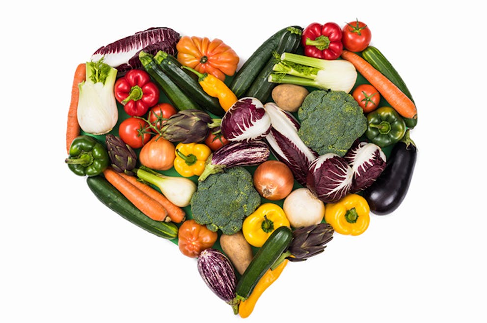 Healthy eating concept with nutritious vegetables in shape of a heart on white background.