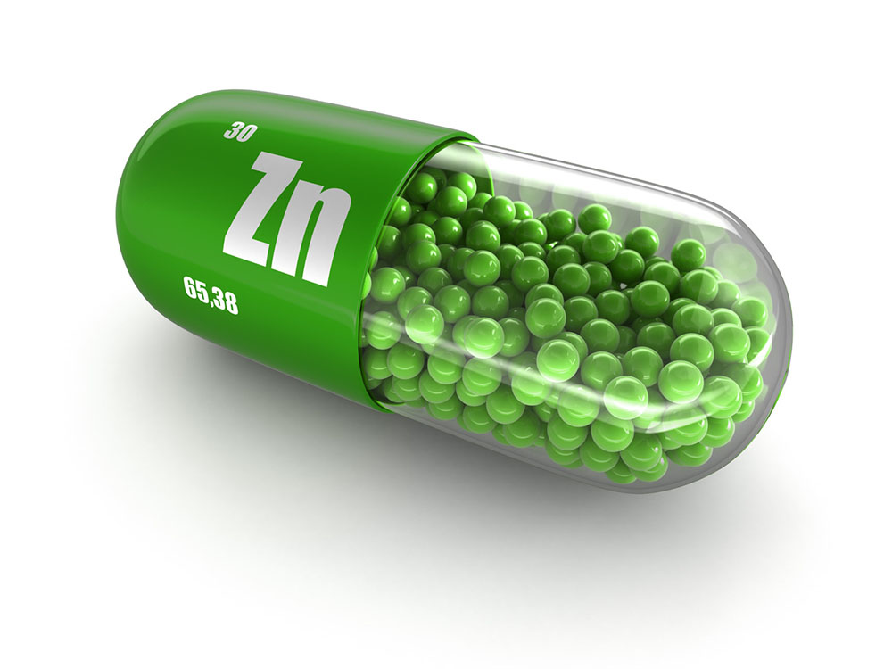 Zinc supplement image with a green capsule labeled with Zn element and atomic number.