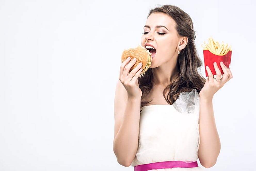 hangry young woman gorging on a burger and fries