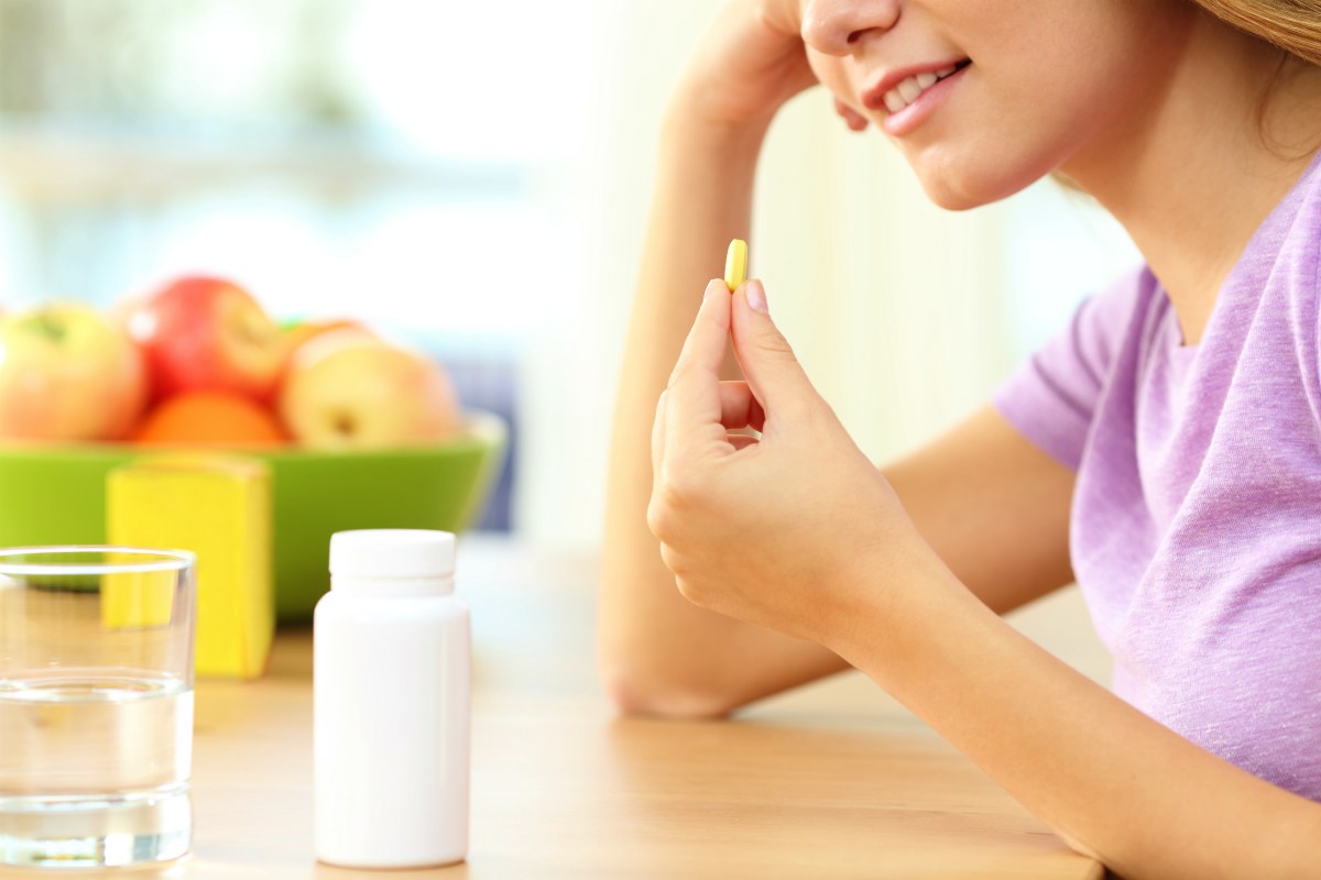 Close up of a girl hand taking vitamin pill on a table at home | The 9 Benefits of Apple Cider Vinegar