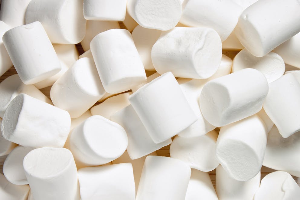 Pile of white, round marshmallows, marshmallow confection treat.