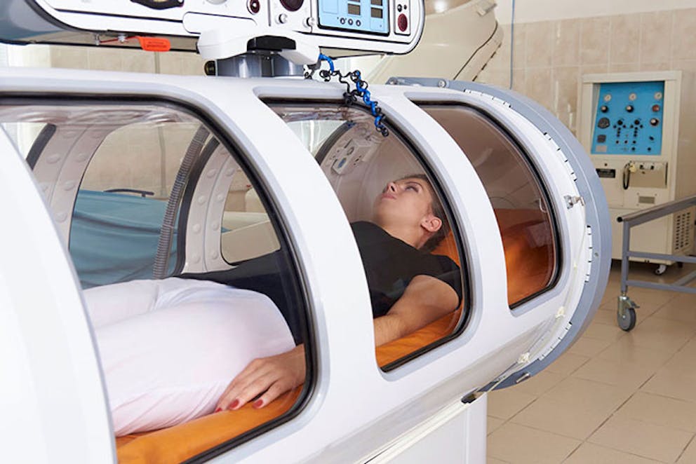 Woman medical patient lying in hyperbaric chamber for HBOT treatment.