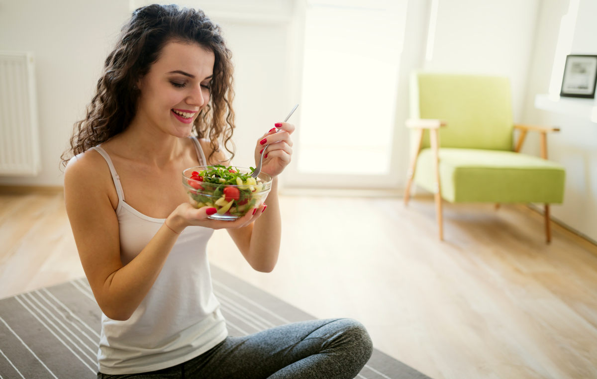 Woman eating healthy salad after working out at home | Best Workouts To Get Rid Of Cellulite Fast