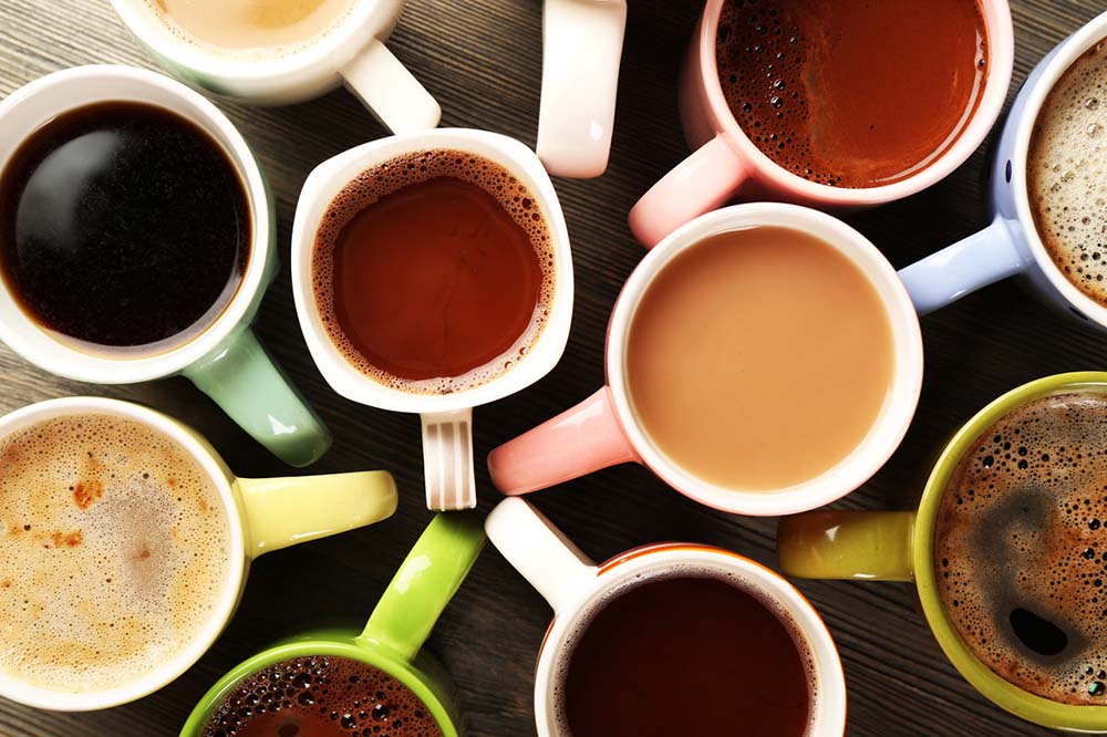 Top view of many mugs in various shapes and sizes filled with coffee and coffee alternatives