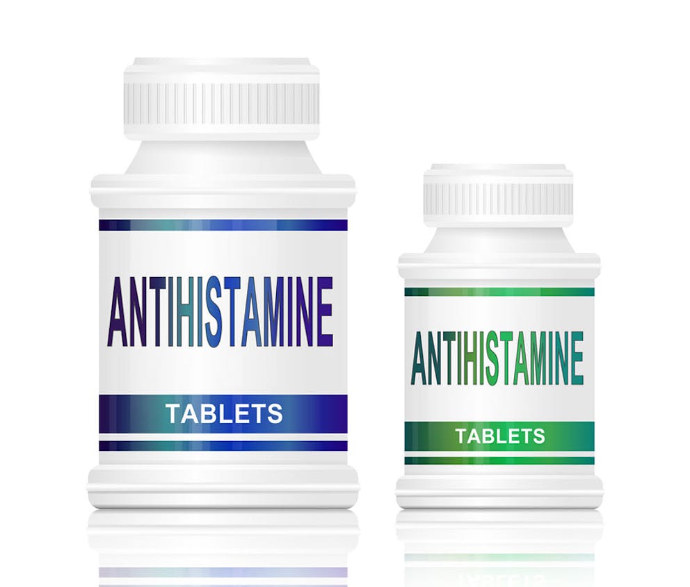 Pill bottles with antihistamine on label, antihistamine medications on white background.