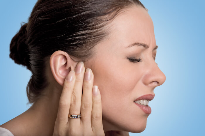 Woman touching her ear in pain.  |  The Best Remedy for An Ear Infections