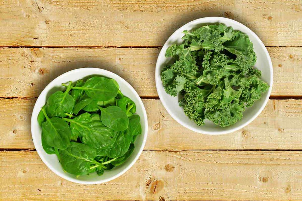 Two white bowls one containing spinach leaves and one containing chopped kale leaves | List Of Starches That Are Worse Than Sugar | complex carbs