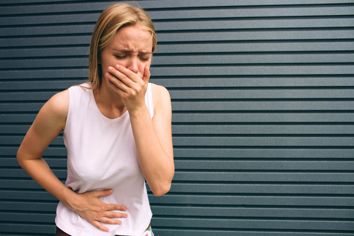 Young woman with hands on stomach | The Dangers Of Using Baking Soda: Sodium Bicarbonate Hazards