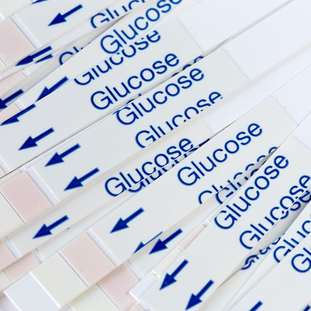a photo of multiple strips of white paper with the word glucose in blue letters