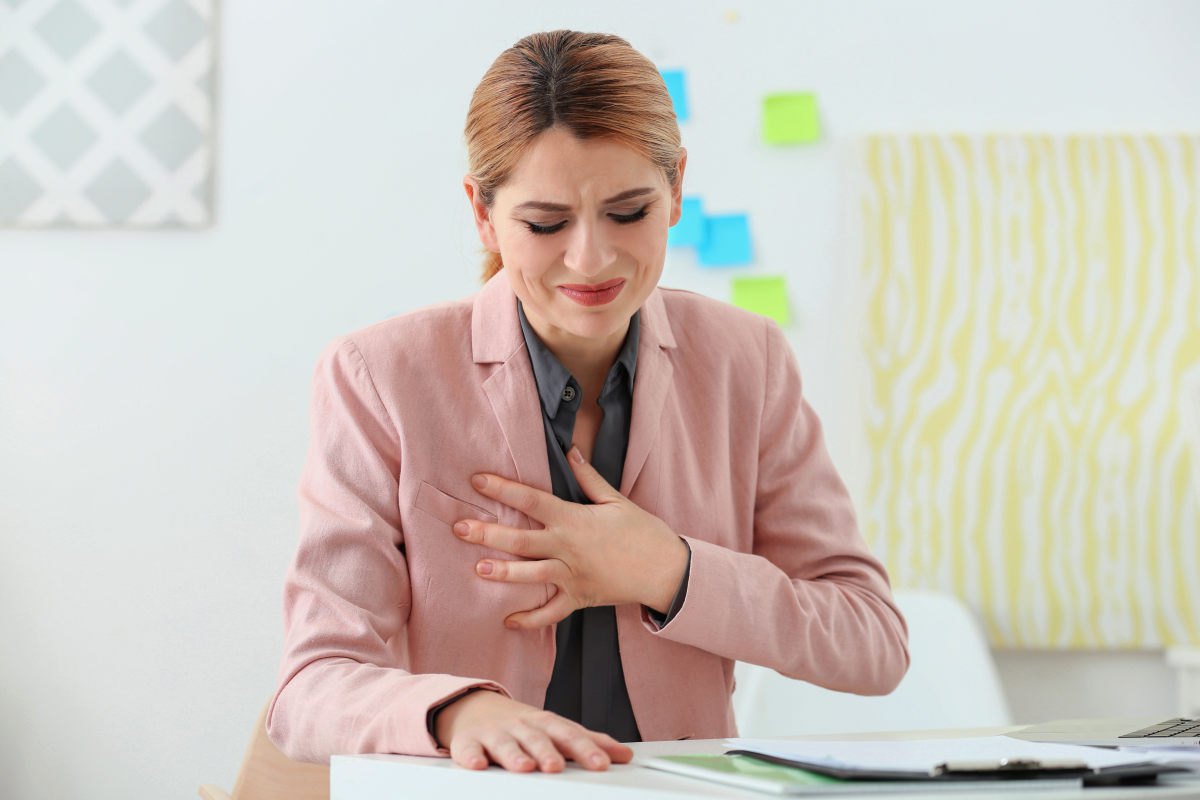 Beautiful woman suffering from heartache in office | The Heartburn Medication Myth