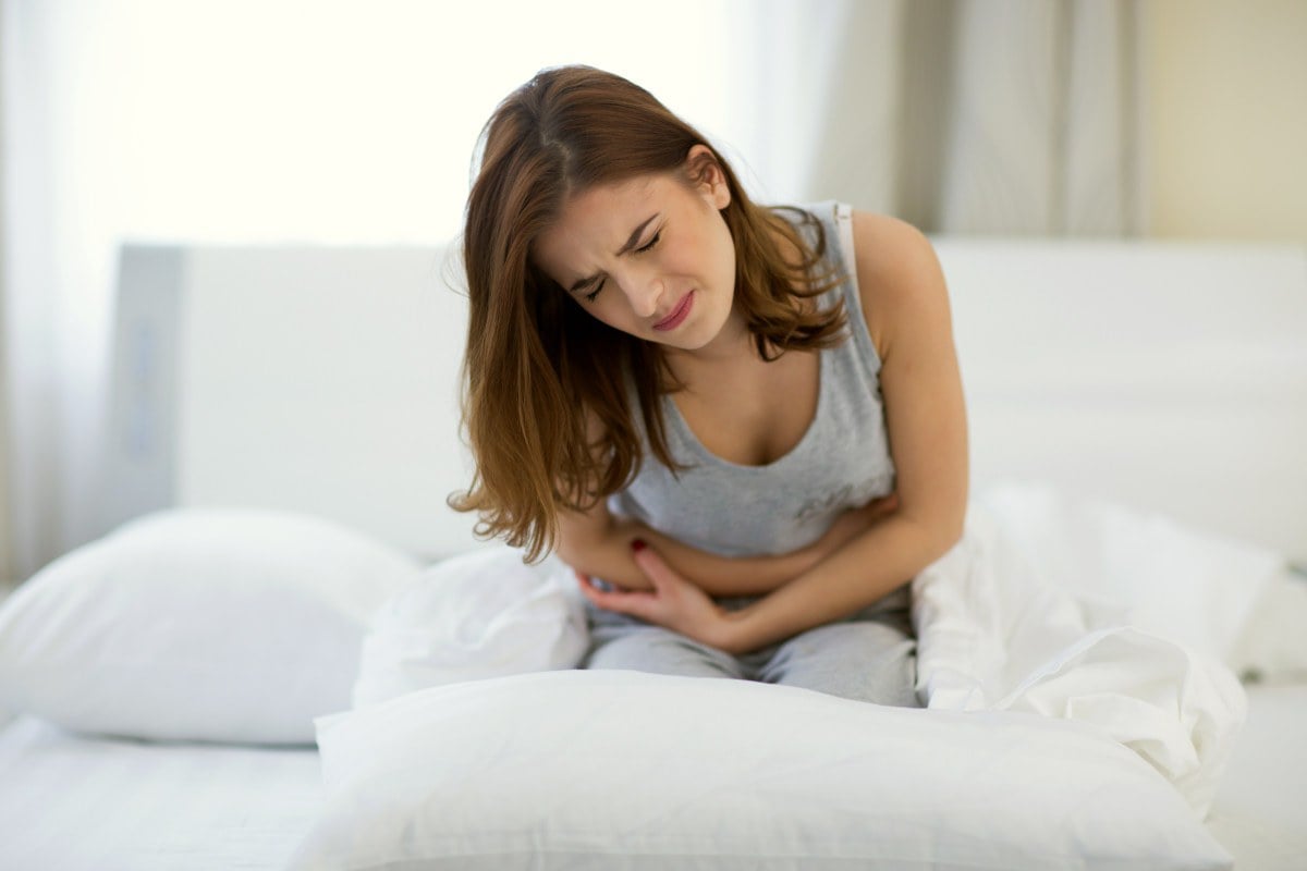 Young woman sitting on the bed with pain | The Hidden Source Of Your Neck And Or Shoulder Pain