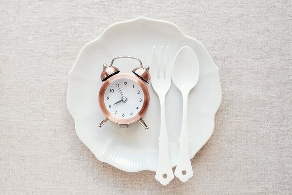 A photo of a clock on a plate with fork and knife