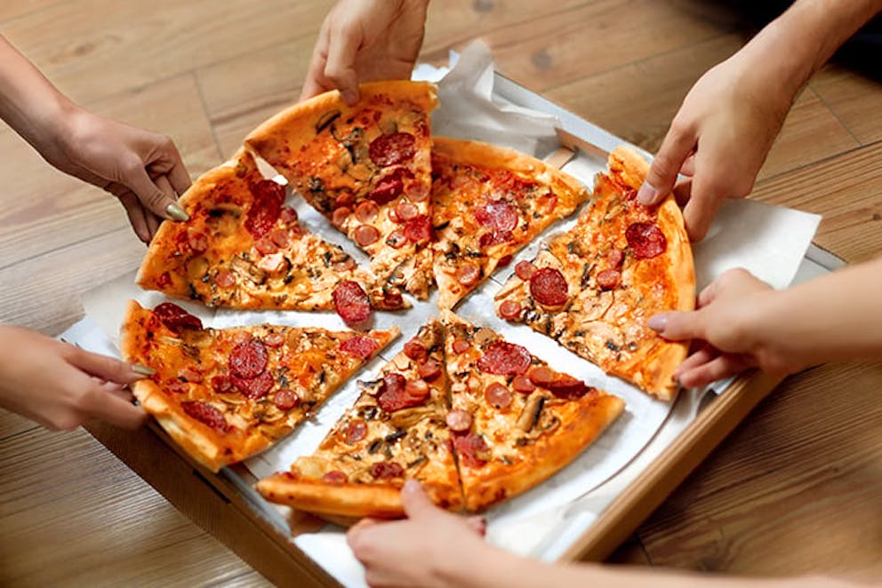 people grabbing slices at a pizza party