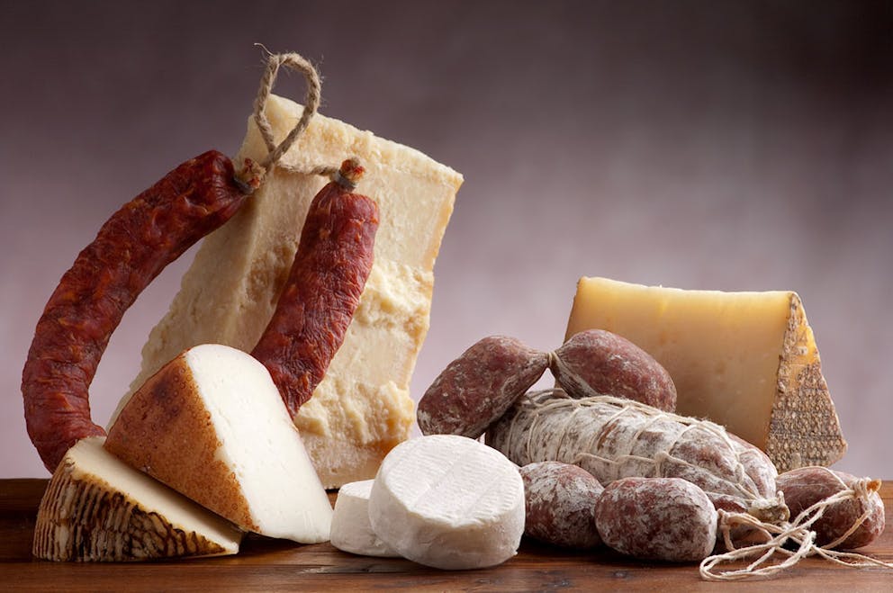 Assorted rustic cheeses and salami and a wooden table.