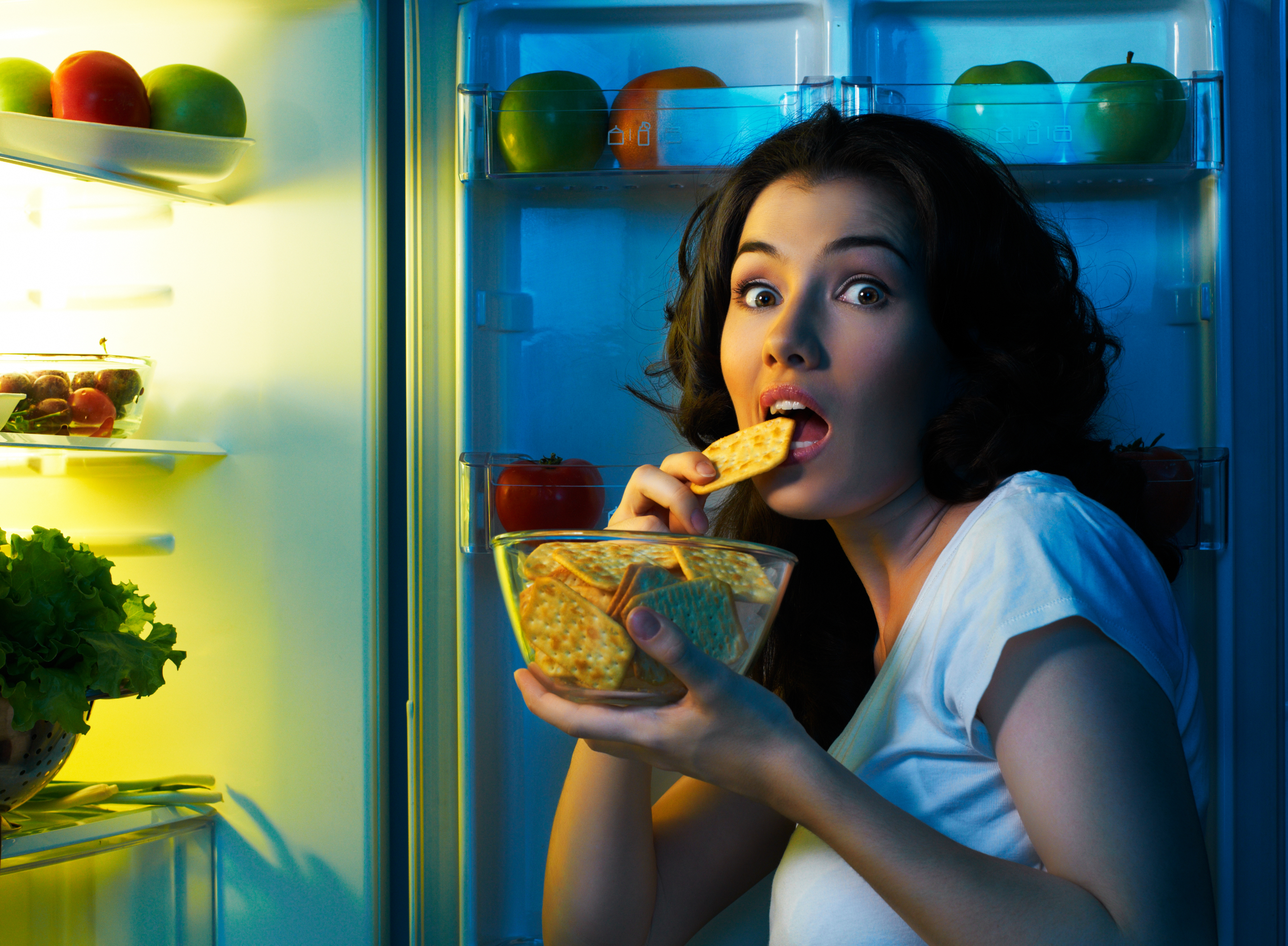 Woman eating crackers in fridge