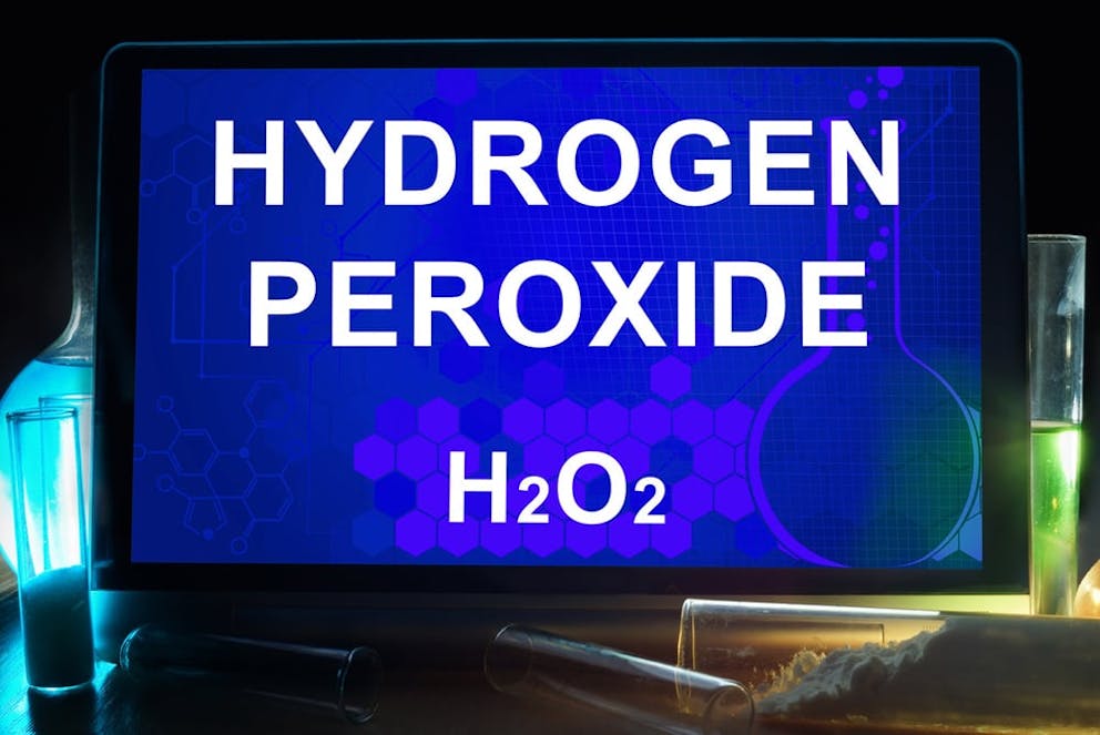Digital tablet next to chemistry tubes that says hydrogen peroxide with chemical formula H202.