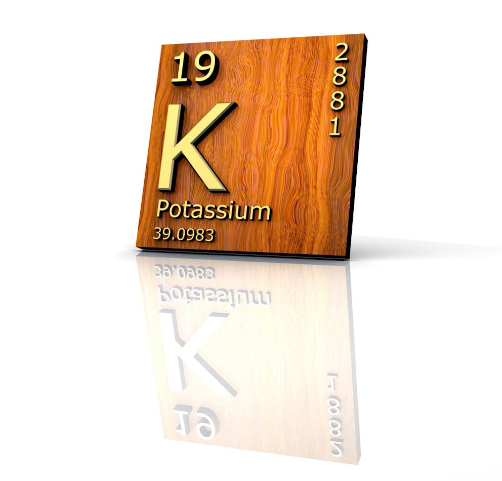 Potassium periodic table of elements mineral information on wood board with reflection.