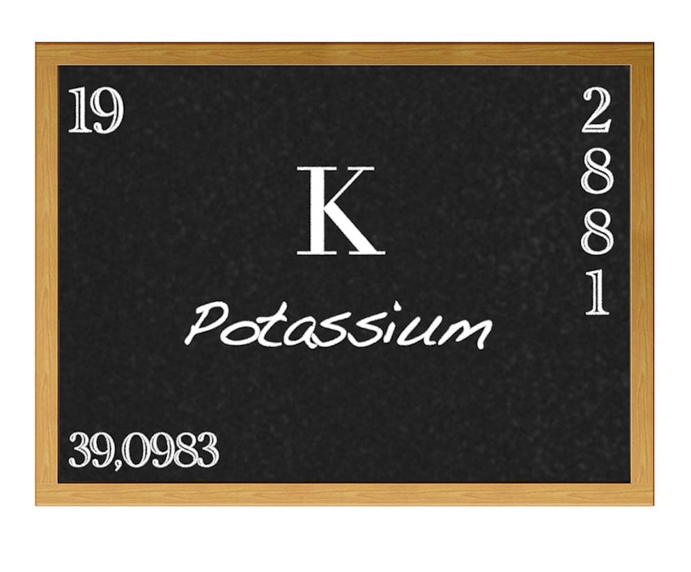 Potassium periodic table of elements mineral information on wood board with reflection.