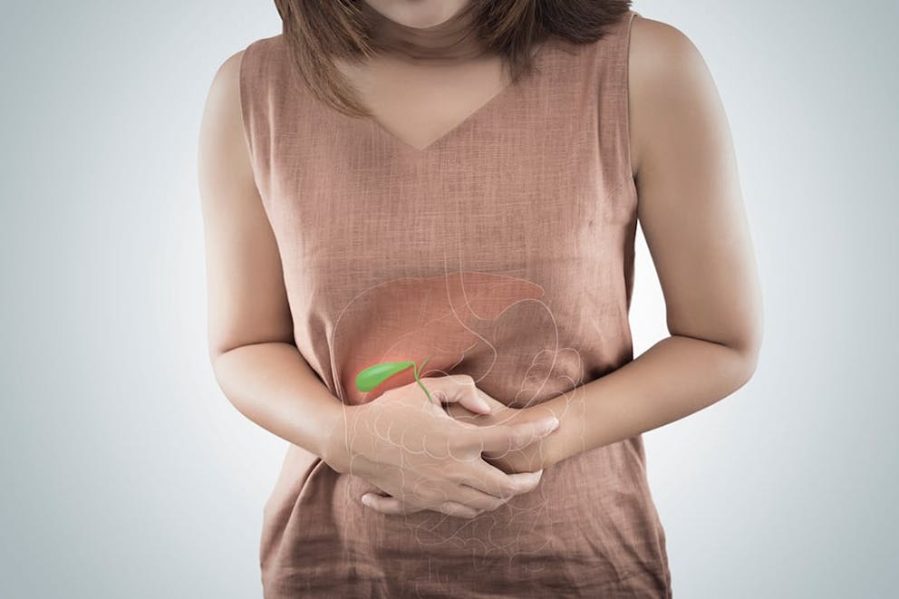 A woman having a gallbladder attack holds her hands to her abdomen with gallbladder pain.
