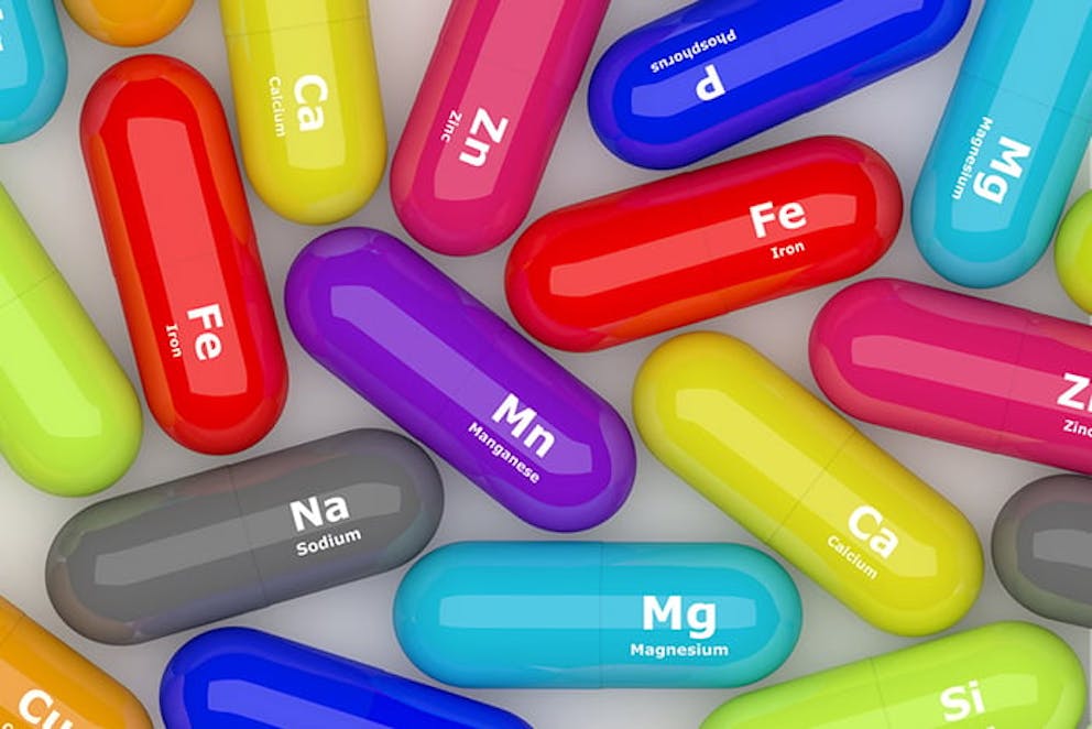 Colorful pills labeled with nutrients your body needs, vitamins and minerals for health.