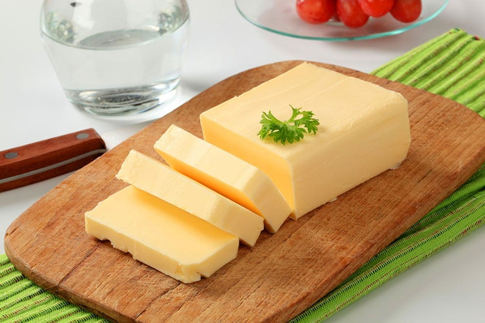a picture of fresh butter on a cutting board garnished with a sprig of green leaves