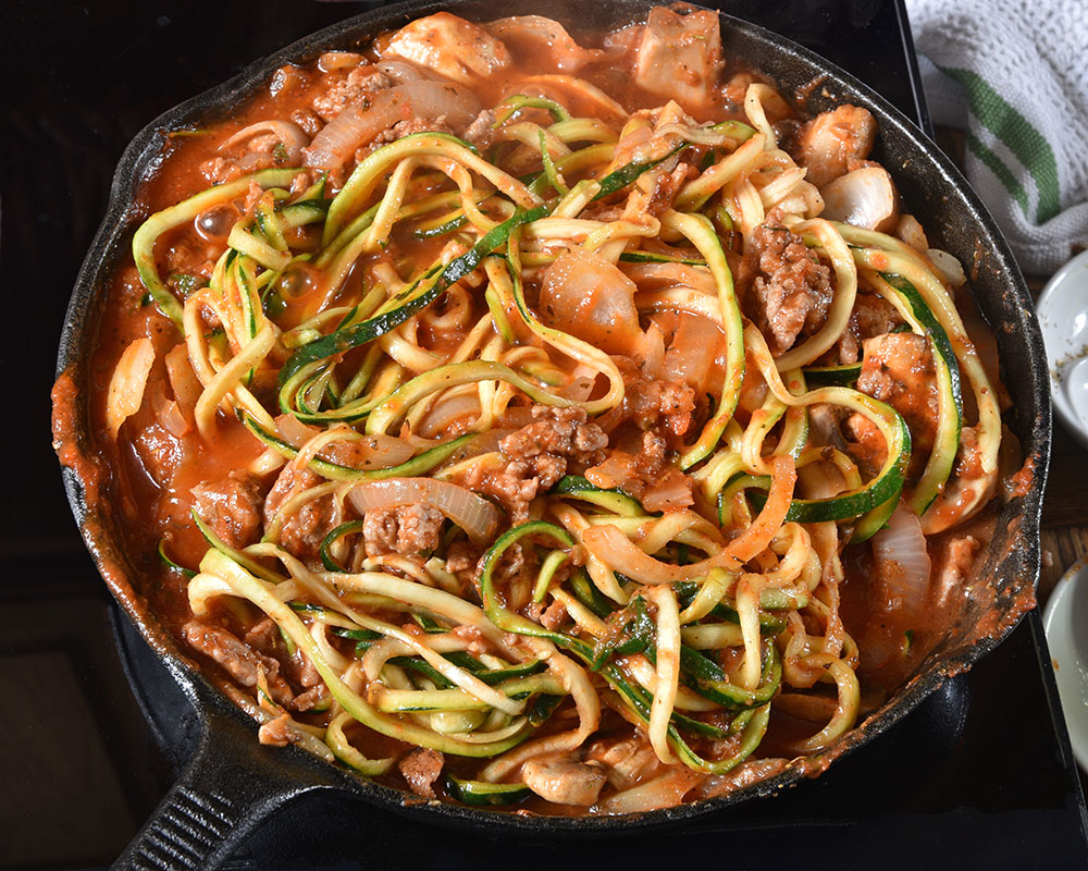 a dish of zucchini spaghetti with meat sauce and vegetables