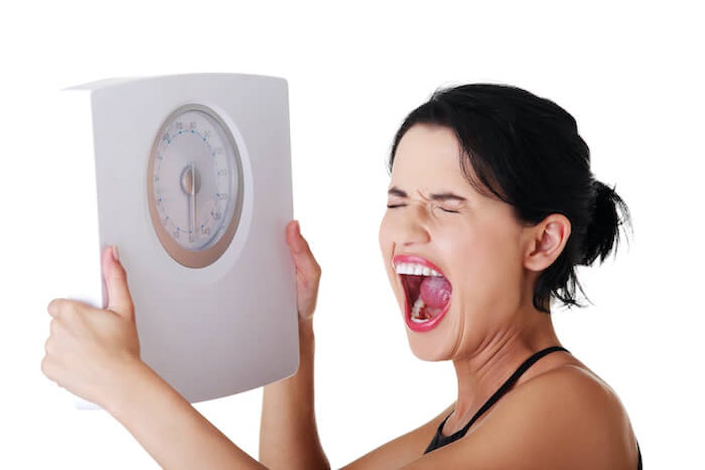 Stressed woman with scale in hands | Will Adrenal Fatigue Cause Weight Gain?