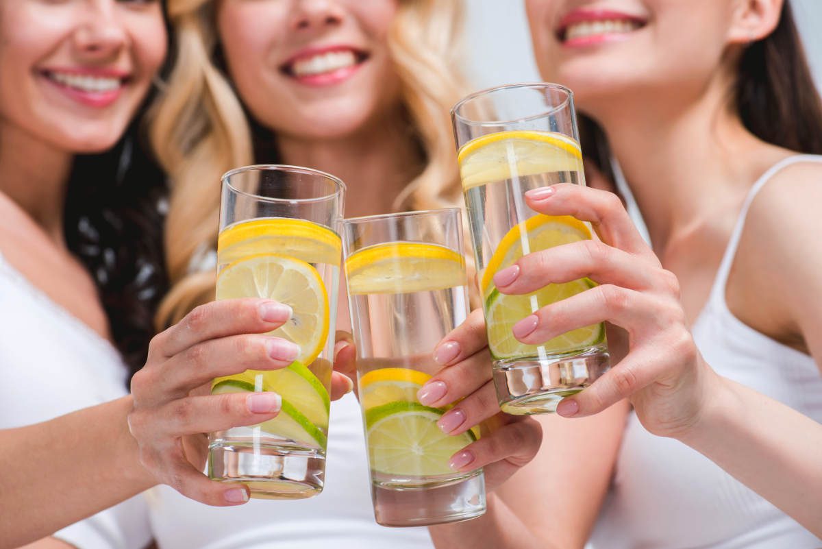 Young smiling women clinking with glasses of water with lemon | Will Lemon Water Kick You Out of Ketosis