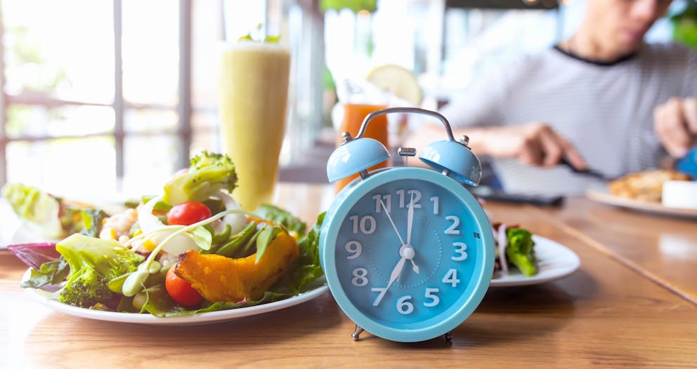 Blue alarm clock in front of a salad plate