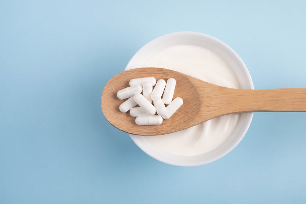 Probiotic and enzyme supplements on a wooden spoon