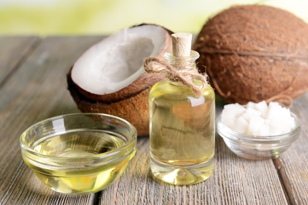 coconut oil bottle next to two coconuts