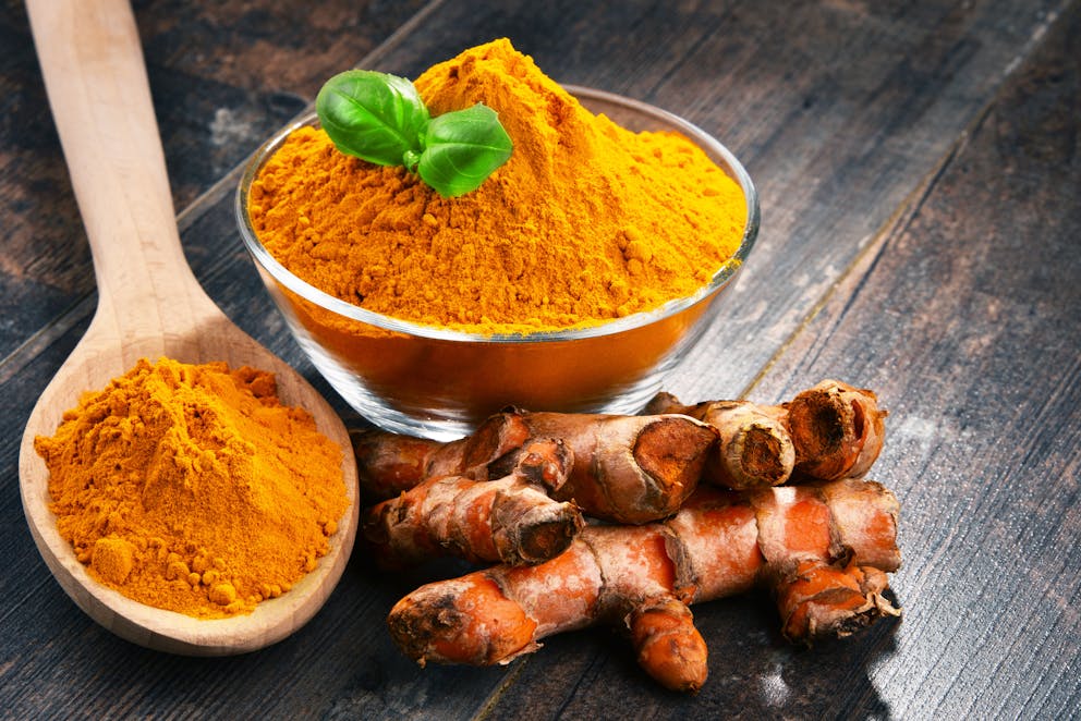 Bowl of turmeric powder on a wooden table