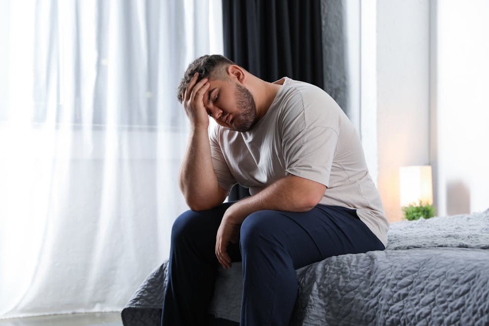 Stressed obese man on the bed