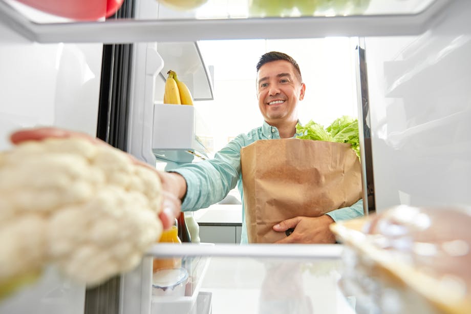 Man placing cauliflower in the fridge