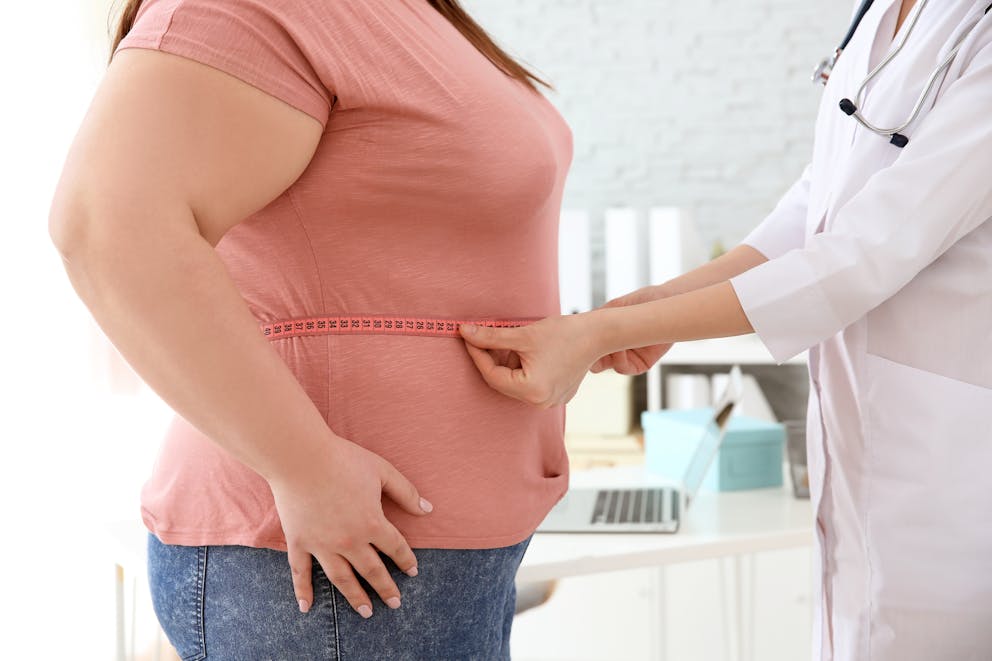 Doctor measuring waist of overweight woman