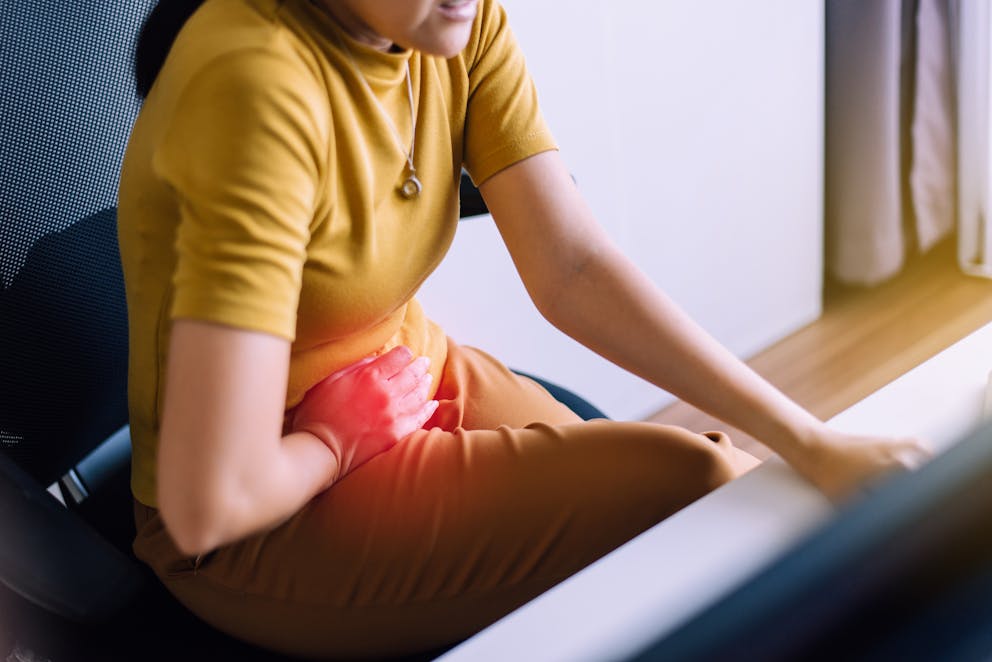 Woman sitting with hand over pelvis