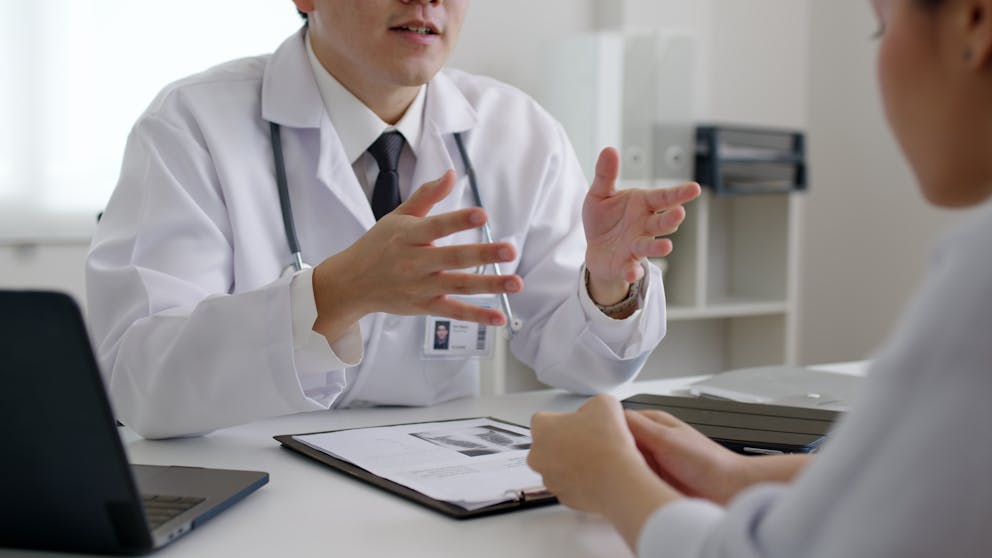 medical service people help talk and discuss medical health record test results at a clinic office desk.