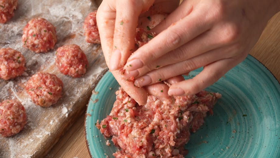 Hands shaping homemade meatballs