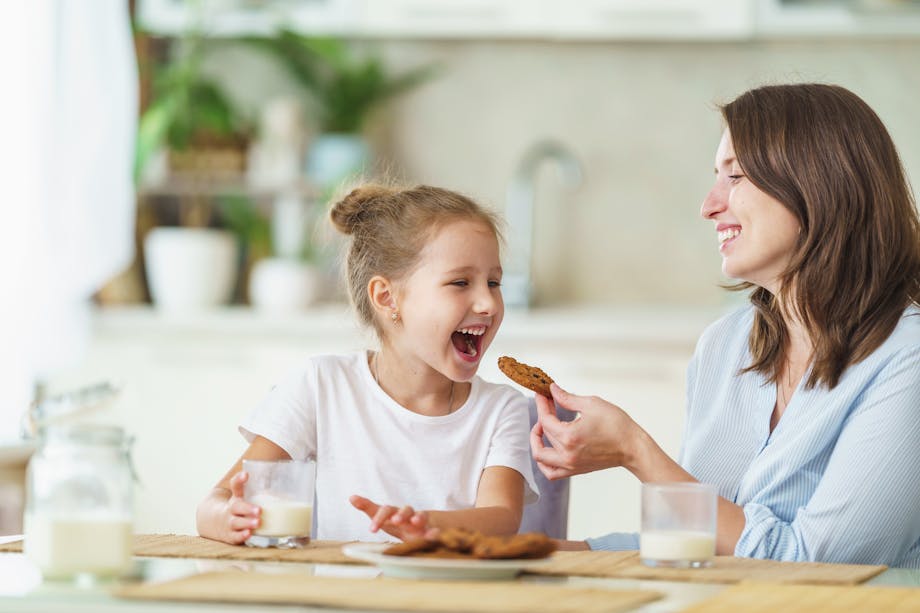 Mom feeding daughter cookies